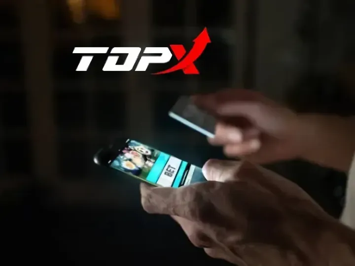 Mãos segurando um celular com a TopX aberta no navegador